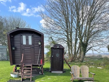 Outside shepherds hut showing the toilet block and seating with fire pit