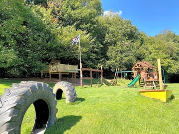 Play area with den, slide, swings, climbing frame and boat sand pit
