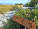 Entrance to mwnt campsite, showing wooden sign and the sea in the distance