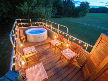 The roof deck and hot tub lit up at night