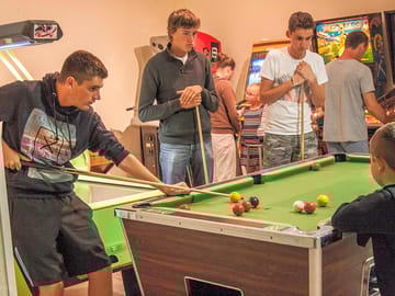 The games room has a pool table and some arcade games