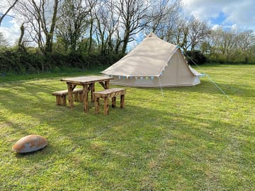 Each bell tent comes with a bench and seating area and a fire pit