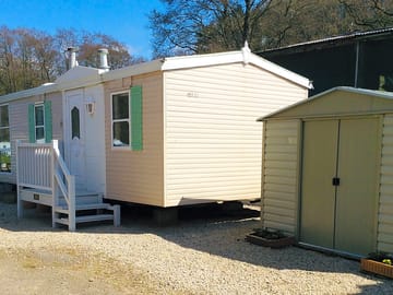 Outside the caravan, with parking space and storage shed