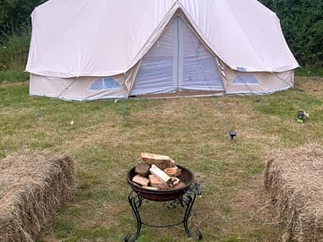 Exterior of tent along with haybale seats and firepit