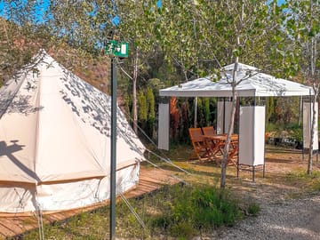 Bell tent exterior with wooden table and chairs