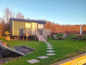 Hut in its garden with solar panels producing electricity to off set your carbon footprint 👣