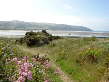 The coast path runs along the edge of the park, leading down to the beach