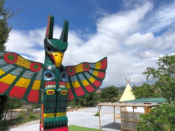 Totem pole with tipi in the background