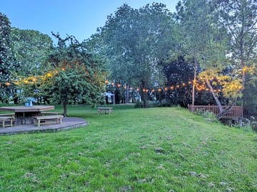 Private garden with decking, picnic tables, parasol, decking over pond, and apple tree.